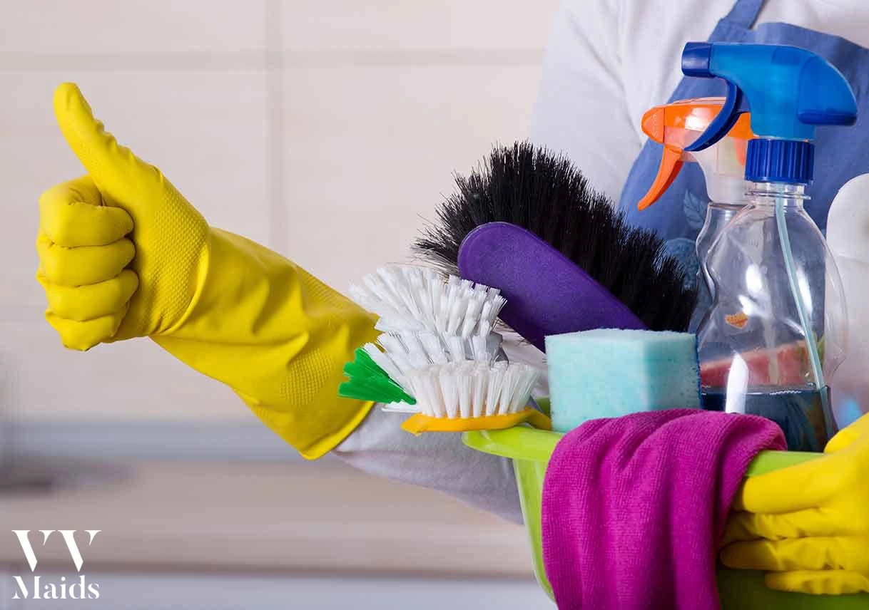 Maid-and-Supplies A person in yellow gloves holds a cleaning caddy filled with various cleaning supplies, representing VV Maids Cleaning Services in NY.