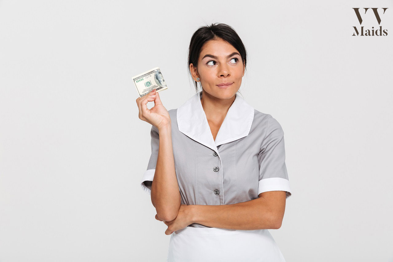 maid holding a dollar bill while looking away thinking