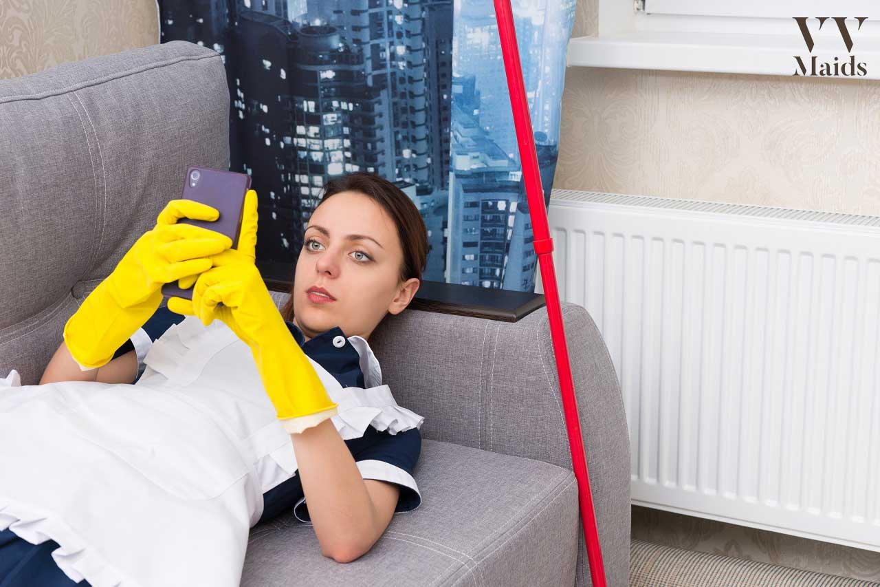 young cleaning lady laying on the sofa while looking at her phone screen