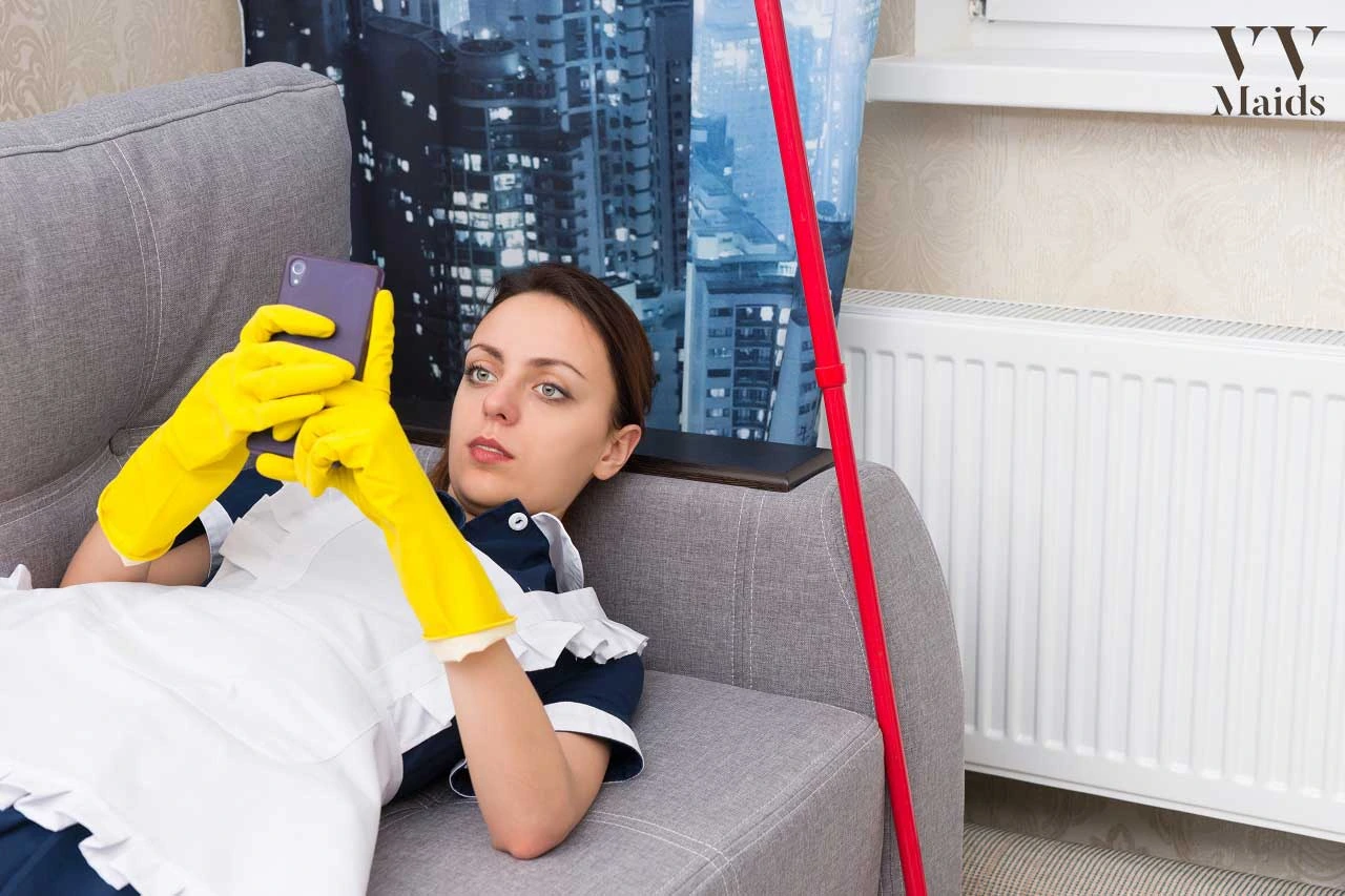 Ways to Find a House Cleaning Service A cleaning professional from VV Maids Cleaning Services in NY relaxes on a couch while checking her phone, wearing yellow