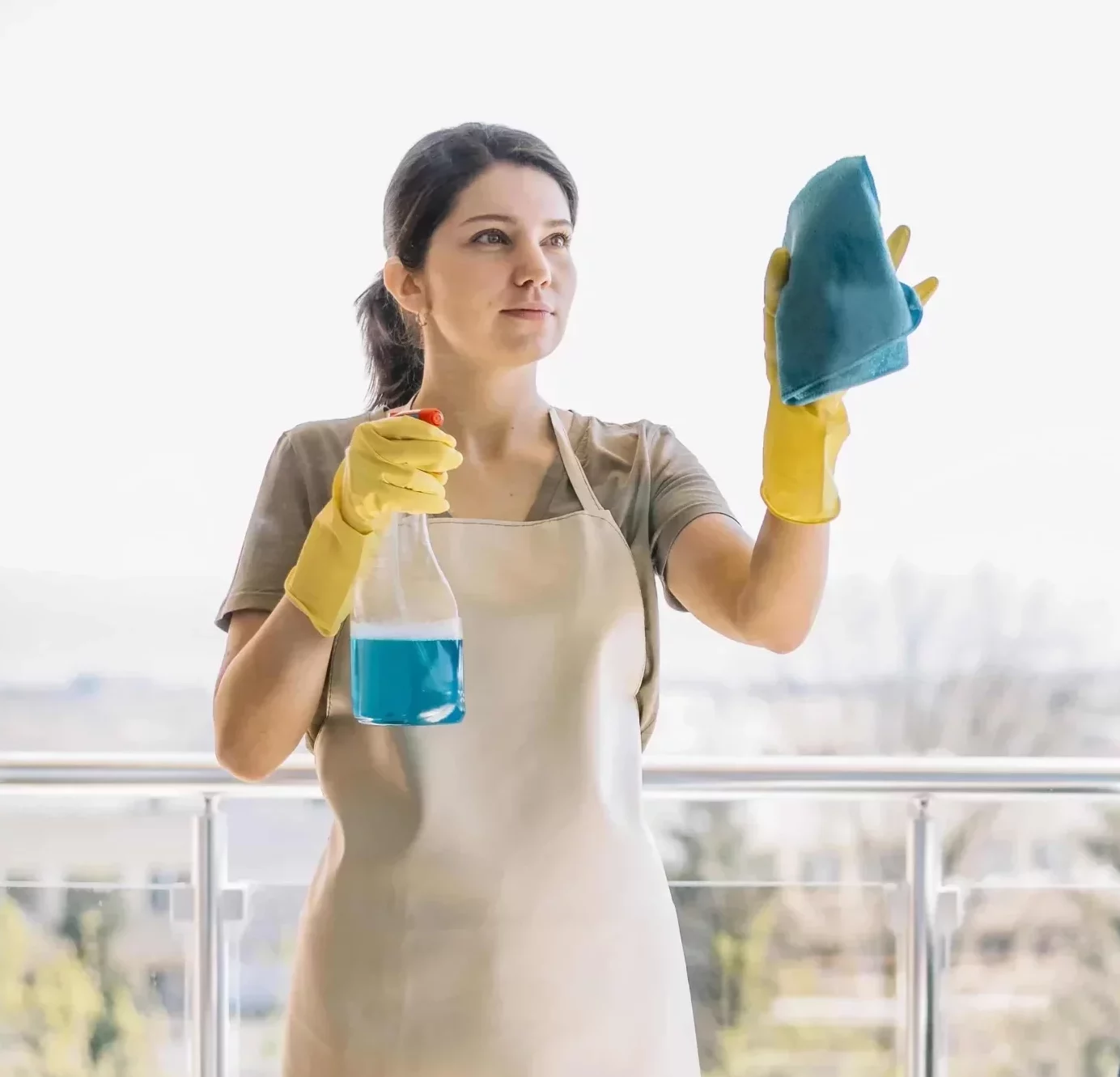 young woman cleaning the windows wearing an apron and cleaning gloves