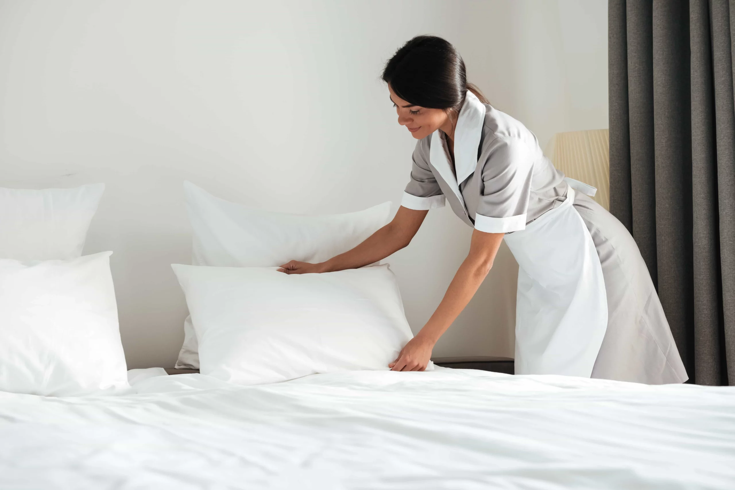 young maid cleaning Airbnb room's bedsheets and pillowcases