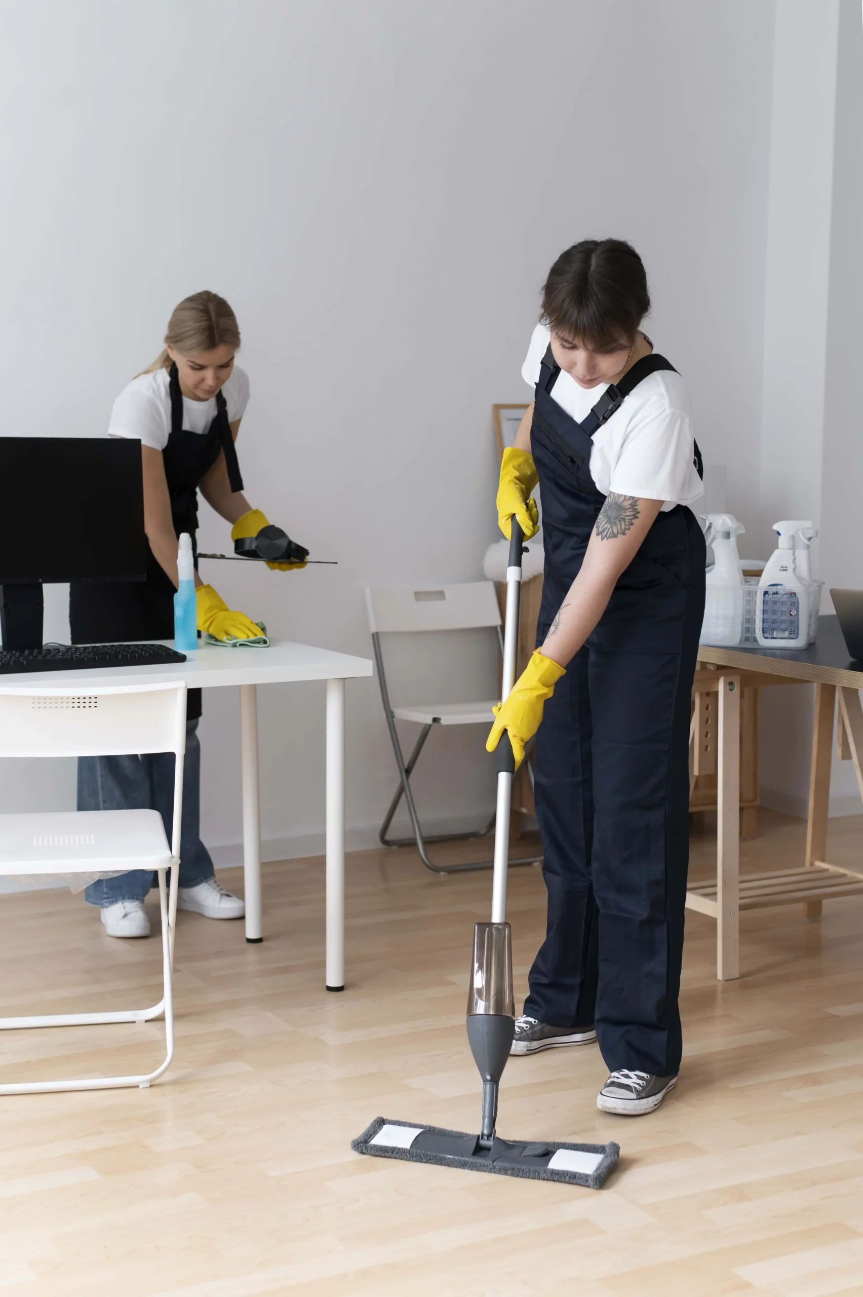 two professionals cleaning an office with wipes and mops