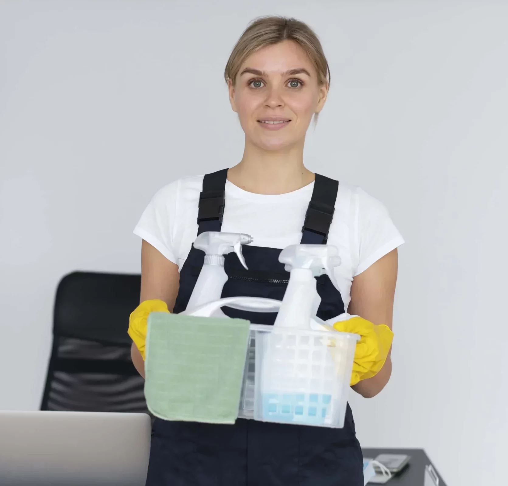 young female professional cleaner smiling while holding a basket full of cleaning products
