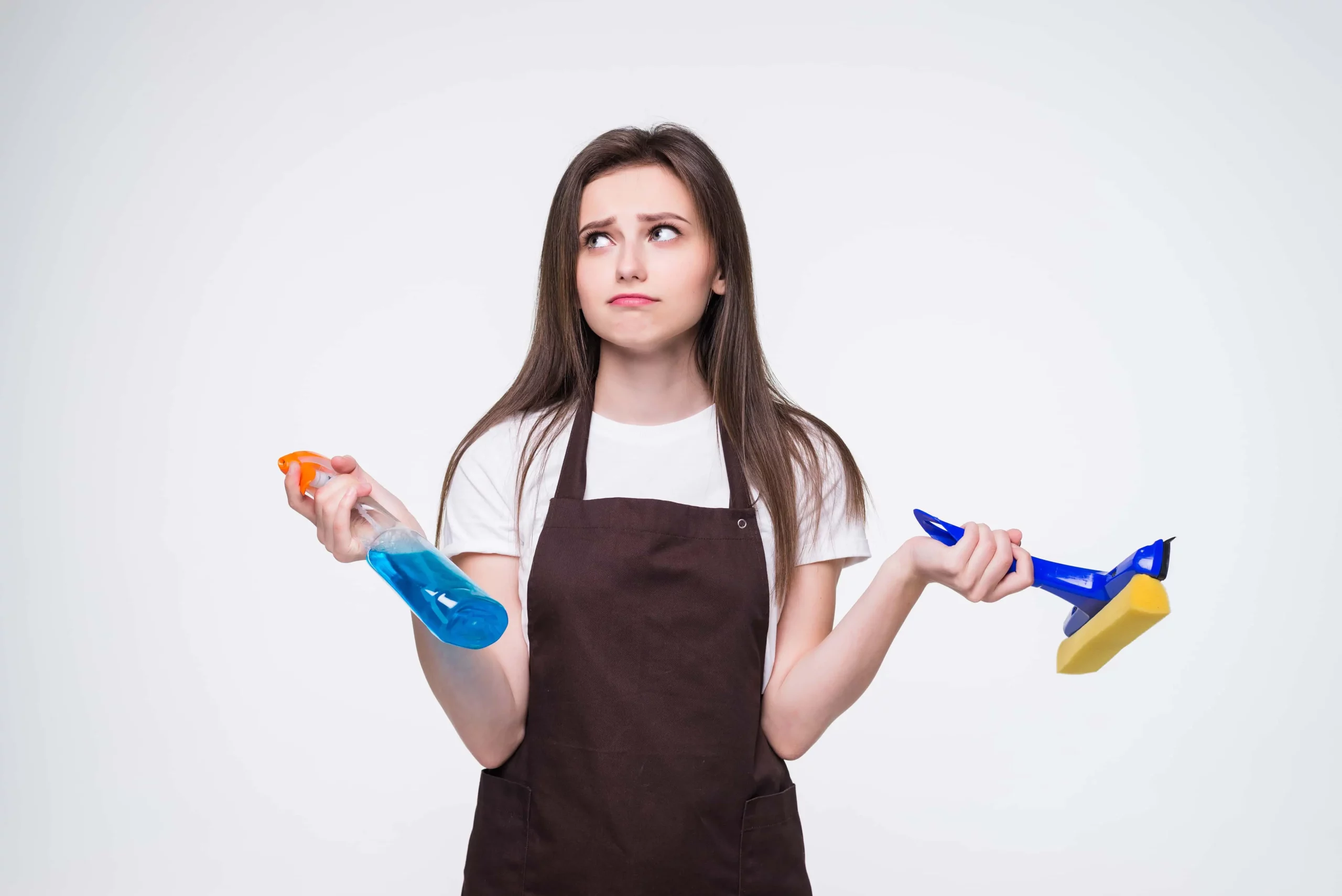 young cleaning lady holding cleaning tools while looking confused