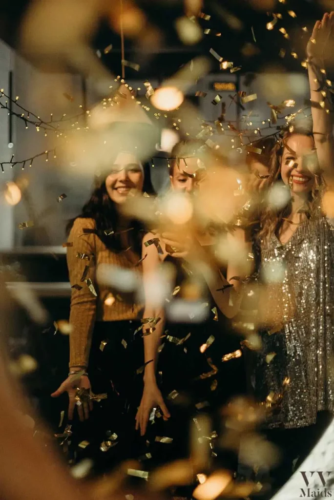 three girls smiling in a party with gold confetti falling on them