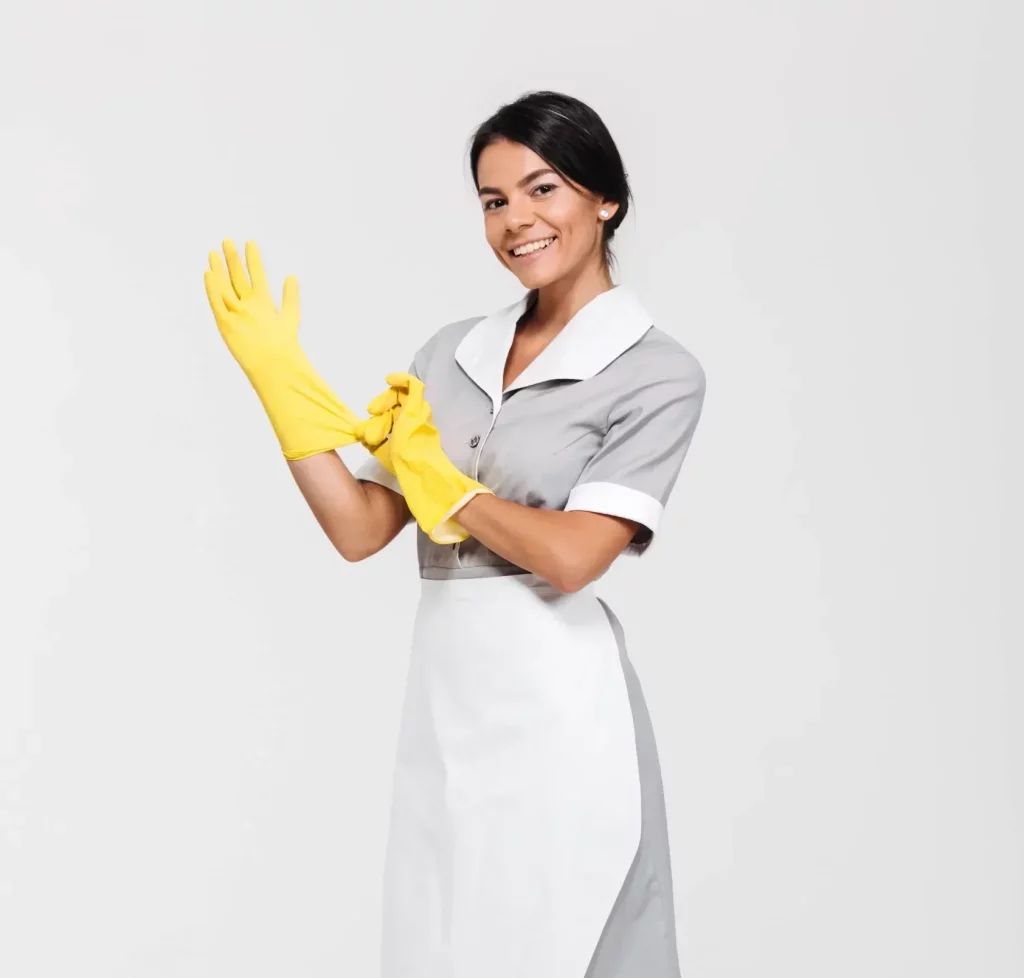 young maid smiling while putting on yellow cleaning gloves